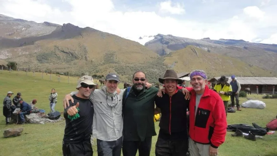 Campamento base al pie de la Sierra Nevada del Cocuy, con el grupo de una expedición de montañismo reunido frente a las montañas nevadas